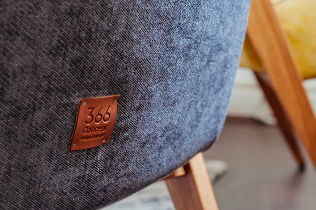 366 Concept logo on the back of a grey mid-century armchair in oak