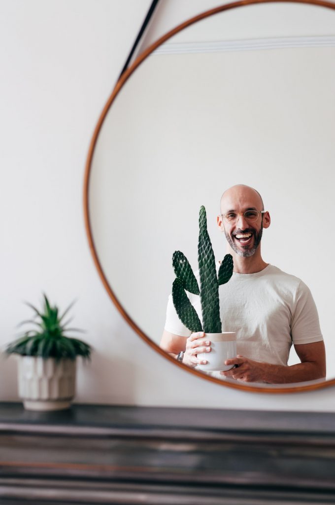 Juan Sandiego holding a potted cactus and smiling