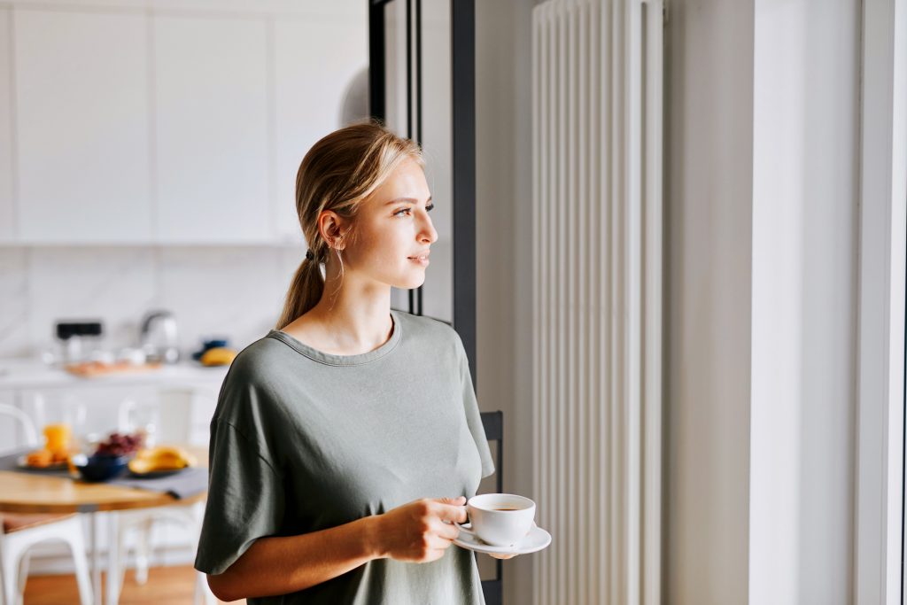A woman has a cup of coffee in her relaxing minimalist kitchen
