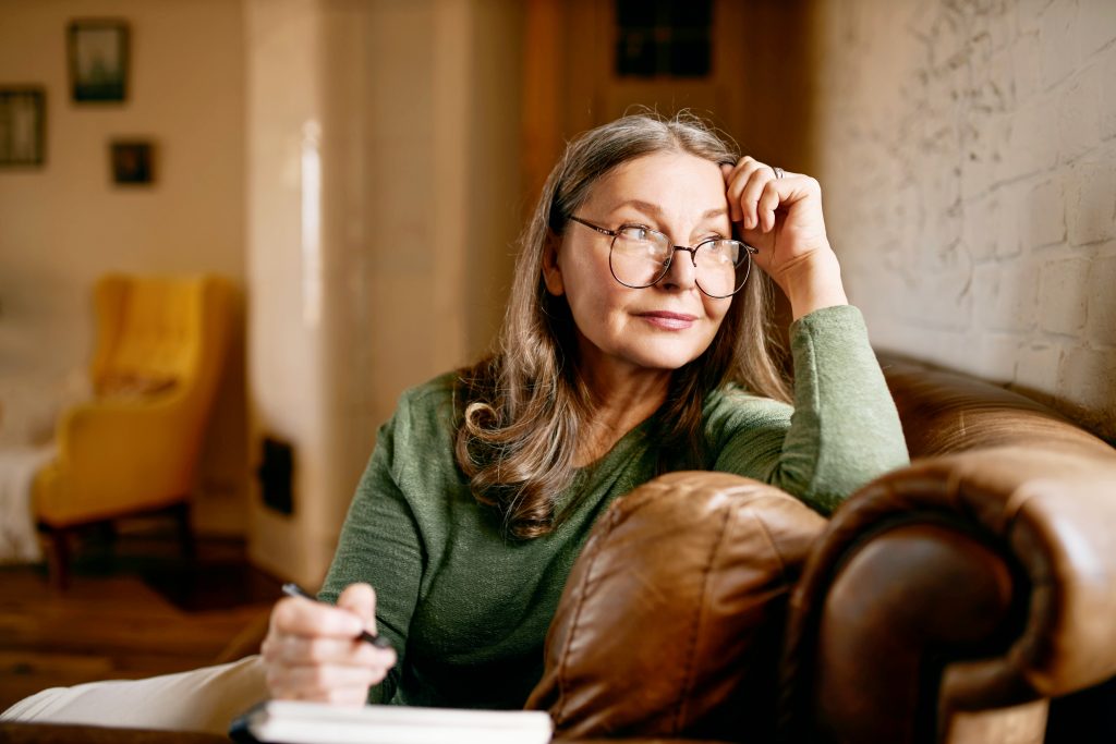 A woman takes notes as she relaxes on the sofa of her calm home